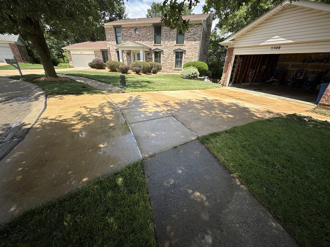 Driveway and walkway mid-cleaning in South County St. Louis, showing the contrast between stained and freshly pressure washed concrete