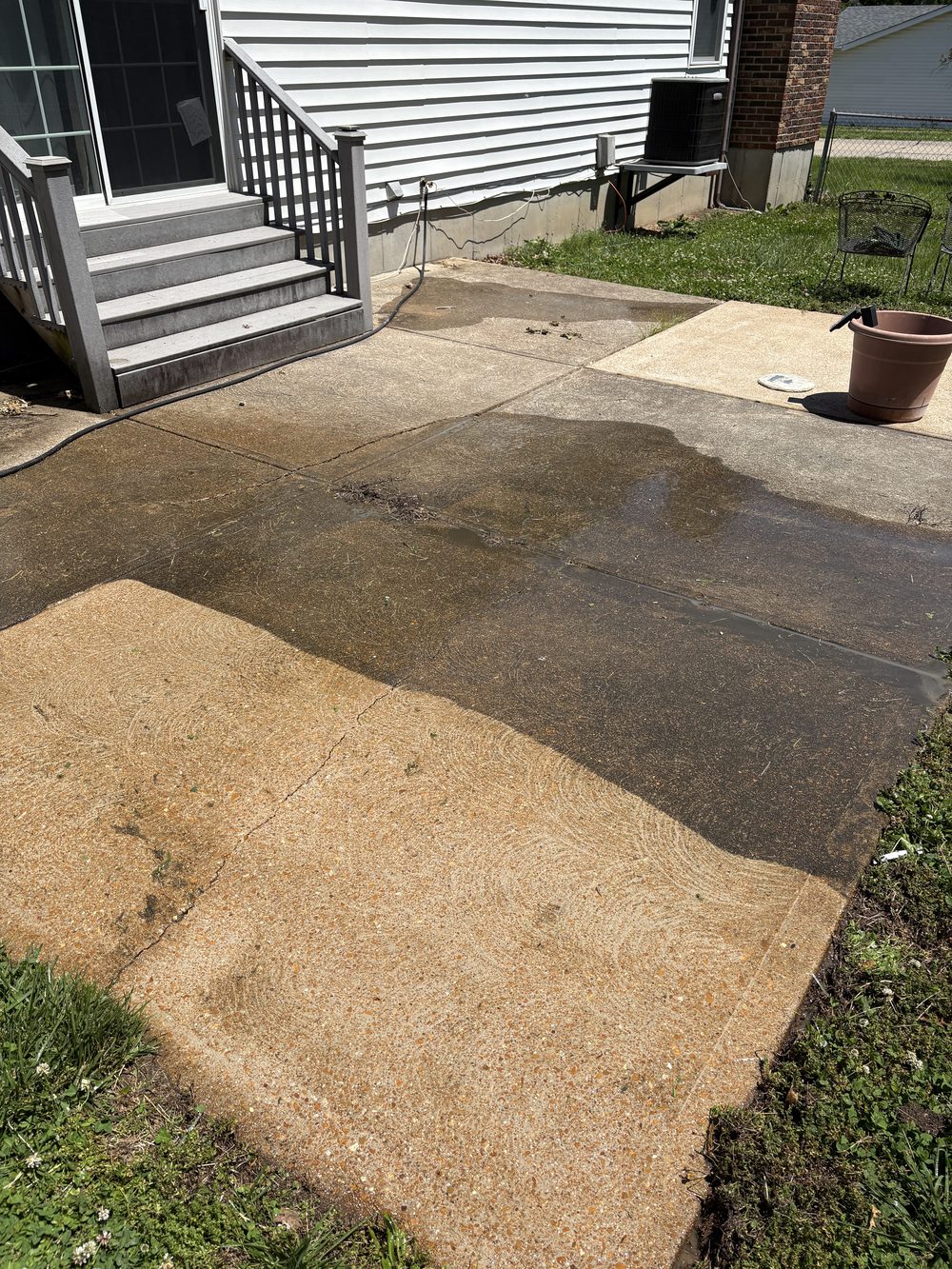 Backyard patio mid-cleaning showing the contrast between stained and freshly pressure washed concrete, South County St. Louis