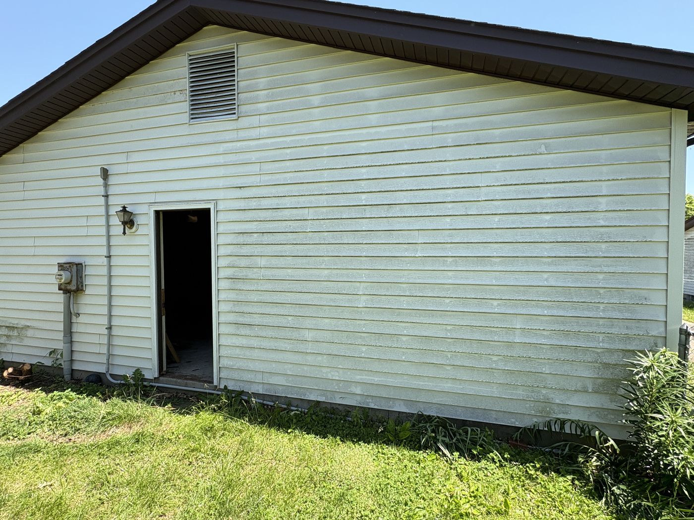 Vinyl siding before soft washing, with green algae and oxidation staining